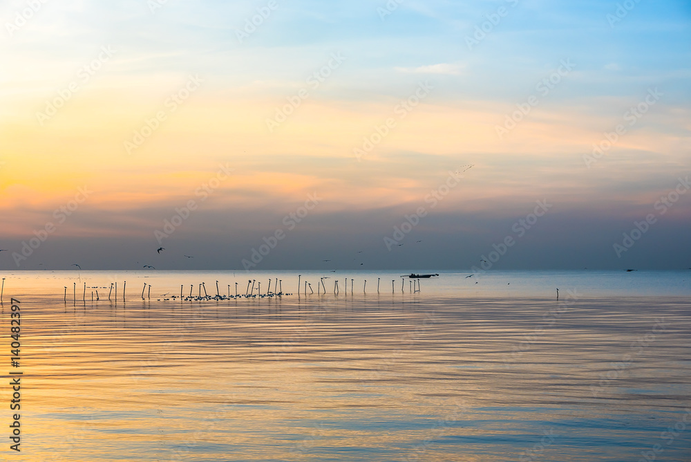 Naklejka premium Boat slow downstream on the water near fence in silhouette.