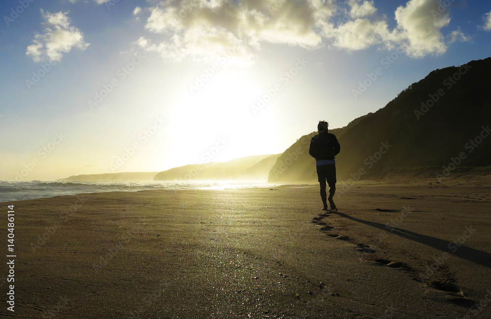 Young man walking down Johanna beach alone on sunset
