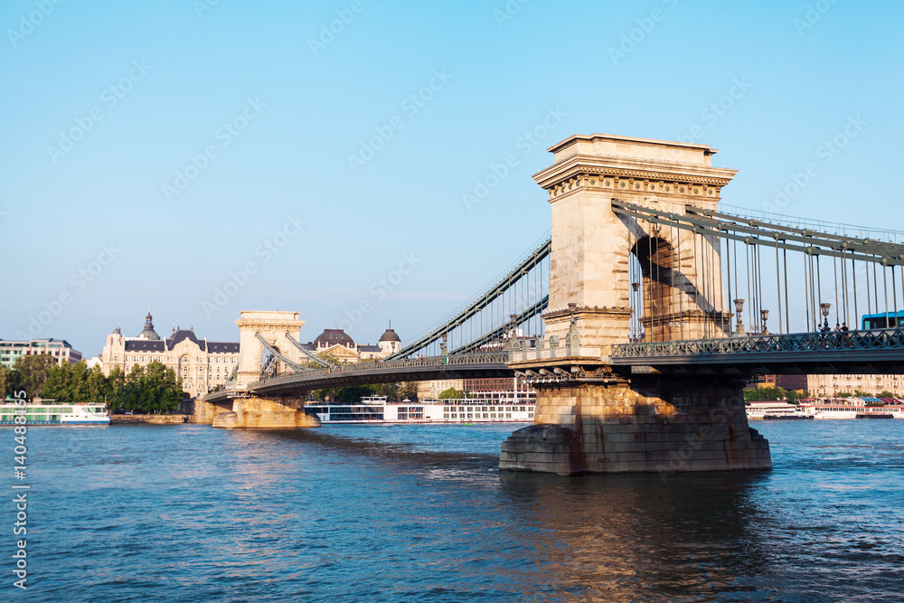 Obraz premium Szechenyi Chain Bridge in beautiful Budapest at sunset. Bridge over the Danube River, connects the two banks of the Buda and Pest, in the capital of Hungary.