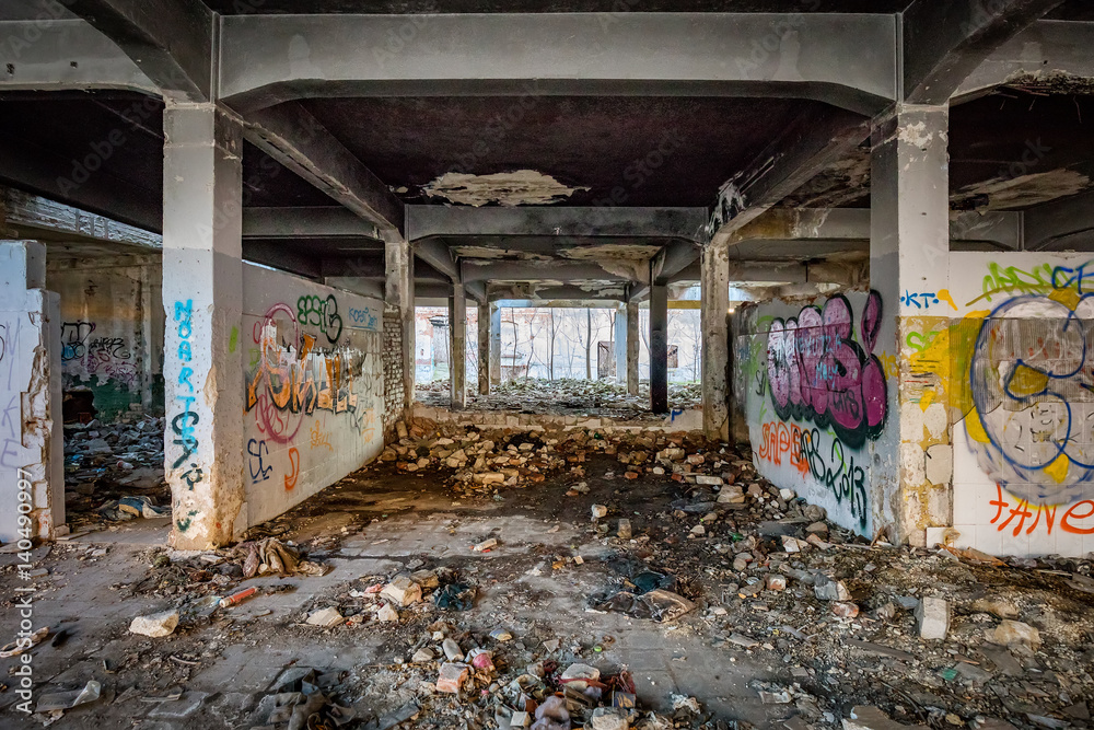 Abandoned building covered in soot and graffiti with ruble and garbage on the floor in an industrial area like a post apocalyptic scene Abandoned building covered in soot and graffiti with ruble and garbage on the floor in an industrial area like a post apocalyptic scene