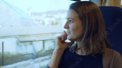 Wallpaper Mural Young girl talking on cell phone on the train. In the window there are views of sea and city buildings Torontodigital.ca