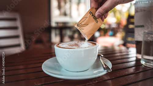 Foto Hand pouring a sugar packet into a cup of coffee.
