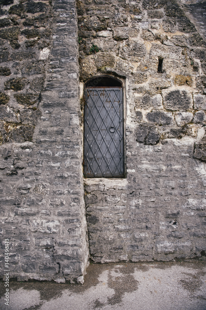 Black iron door with handle in ancient stone wall