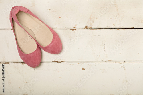 Pink women's shoes (ballerinas) on wooden background.