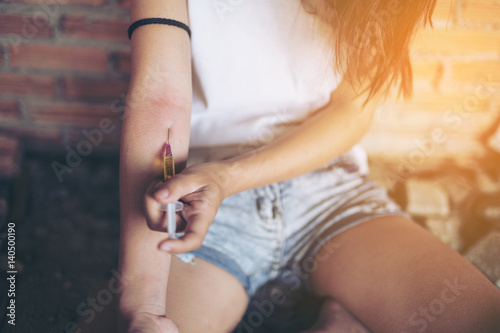 Drug addict young woman with syringe in action