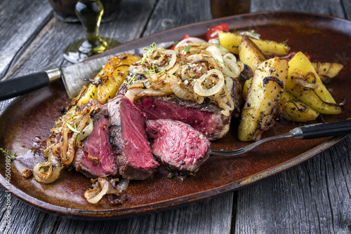 Kobe Entrecote Steak very rare with fried Onions and Potatoes as close-up on a Plate photo