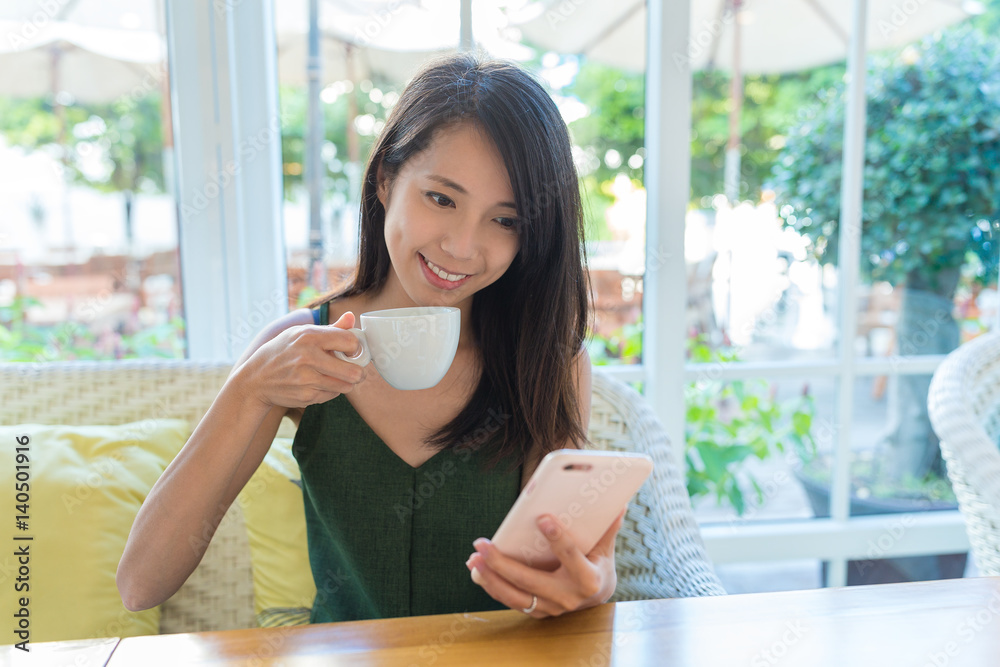 Woman enjoy her coffee and looking at cellphone in coffee shop Woman enjoy her coffee and looking at cellphone in coffee shop