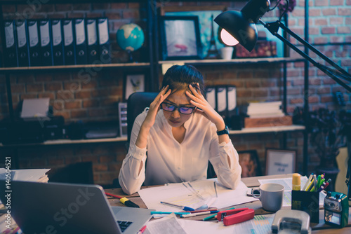Asian women are stressed out of work. She is in the office at night photo