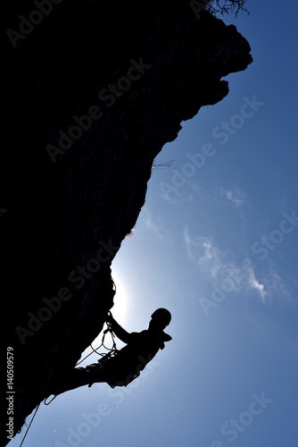 Silhouette of a rock climber hanging on the wall