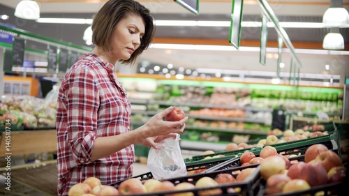 Beautiful woman shopping red apples in supermarket