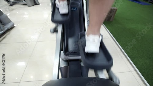 sport, fitness, lifestyle, technology and people concept - close up of men legs walking on treadmills in gym
