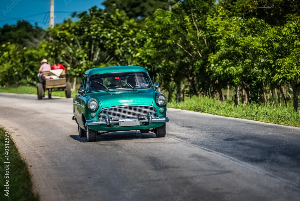 HDR - Oldtimer fährt auf der Landstrasse von Santa Clara in Kuba mit Pferdekutsche im Hintergrund - Serie Kuba Reportage
