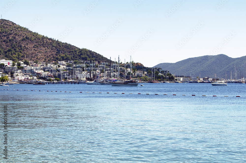 Luxury yachts and sail boats parked in front of Bodrum - Icmeler city in a sunny summer day. The city is on the Bodrum Peninsula, stretching from Turkey's southwest coast into the Aegean Sea.