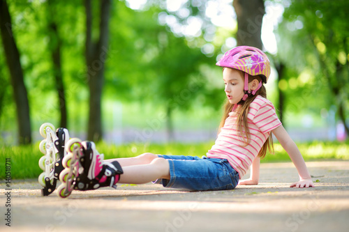 Pretty little girl learning to roller skate on beautiful summer day in a park © MNStudio