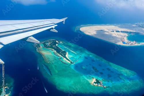 Aerial view of tropical islands and atolls in the Maldives from a plane window