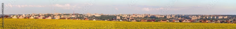 Large wide panorama of the southern residential district of Belgorod city. White city, Russia. Skyline of the city on hills behind a sunflowers field.