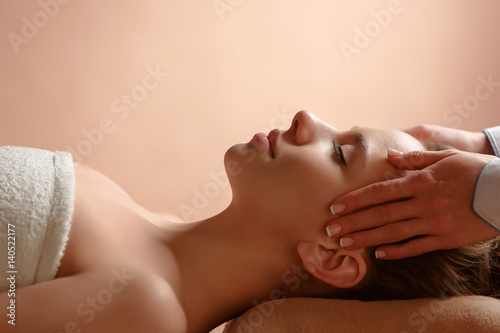 Girl massage therapist doing head massage beautiful brunette girl