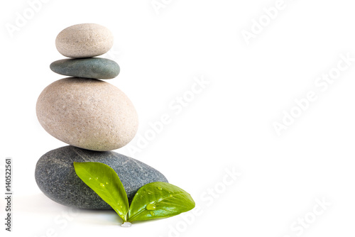 Pyramid of stones with green natural leaves with water drops. White isolated background. SPA and healthcare concept