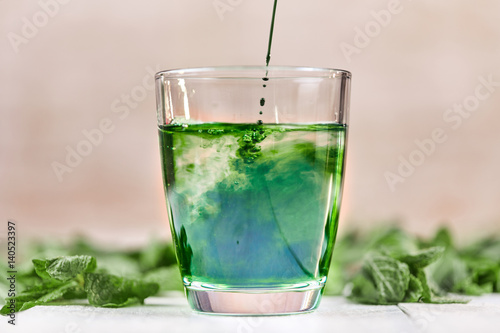 Green chlorophyll drink in glass with water photo