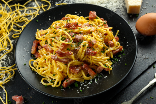 Classic Homemade Pasta carbonara Italian with Bacon  eggs  Parmesan Cheese on black plate.