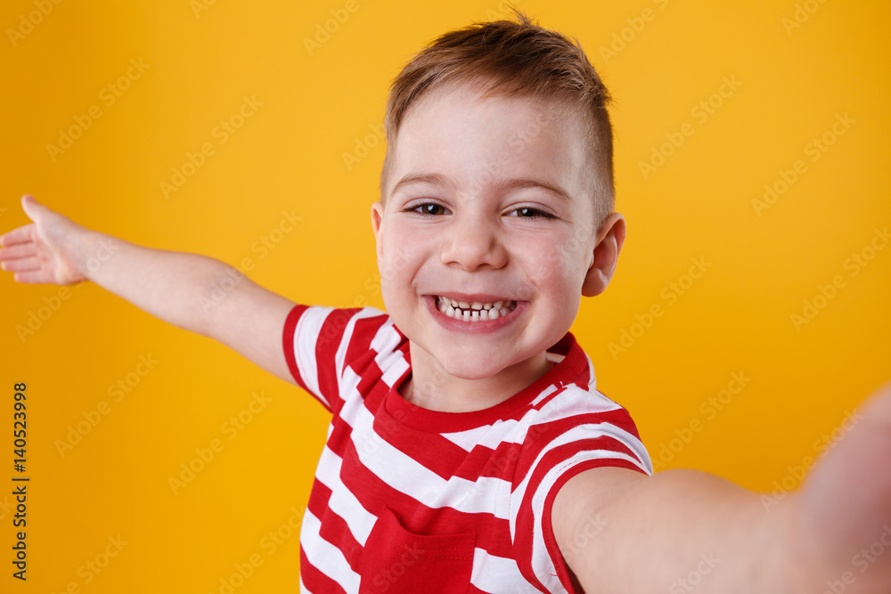 Smiling little boy holding mobile phone and making selfie Smiling little boy holding mobile phone and making selfie
