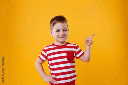 Smiling happy boy pointing finger up at copyspace
