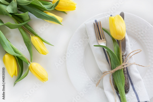 Spring concept with copy space for your. Decorative place setting with yellow tulip on a white background.