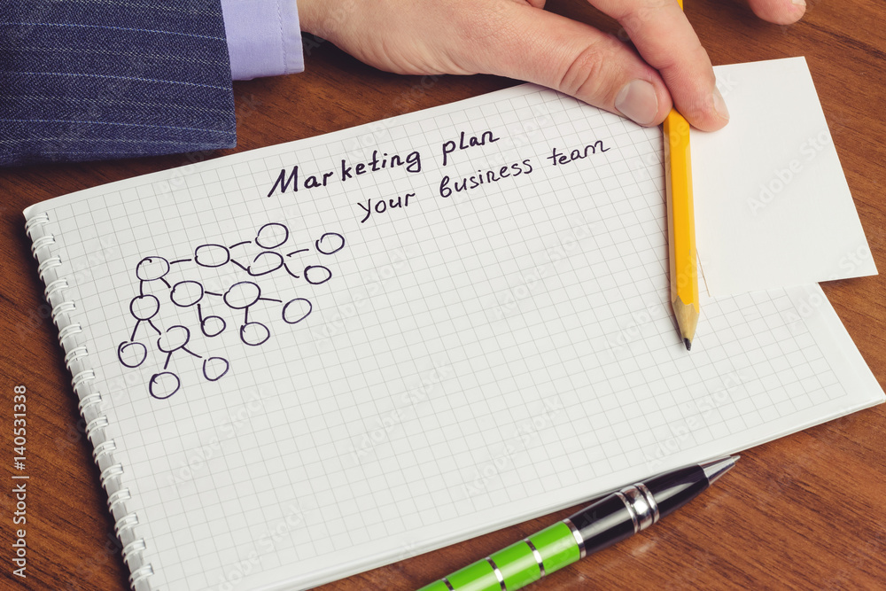Man shows presentation of business concepts network marketing and business structures diagram in notepad on the table. Man shows presentation of business concepts network marketing and business structures diagram in notepad on the table.