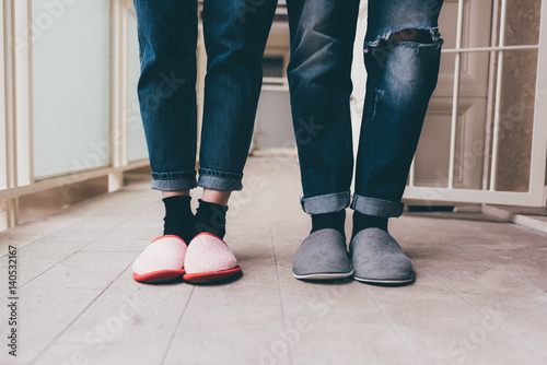 Feet of a couple of young man and woman wearing slippers indoor apartment photo