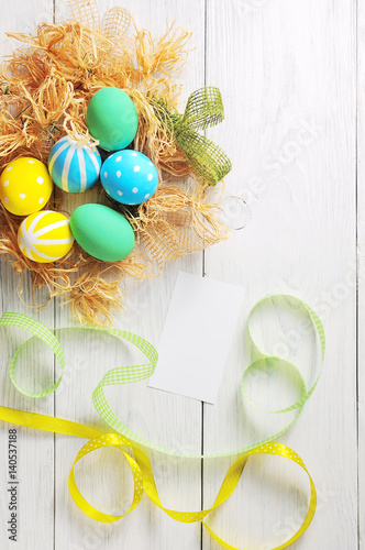 Easter eggs in the nest on rustic white background