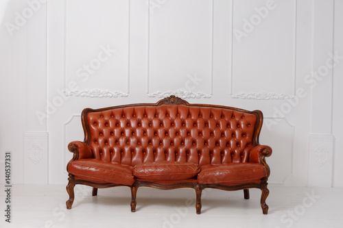 Vintage leather sofa on a wooden floor white stucco on a white background