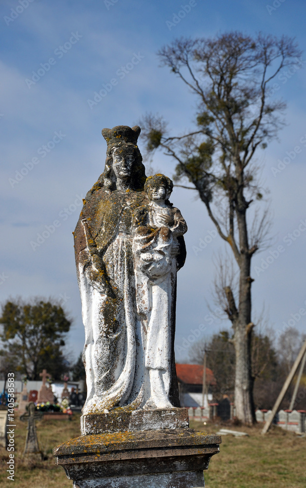 Stone figure of Our Lady with little Jesus on a very old cemetery in the village Yabluniv Husyatyn area in Ukraine.