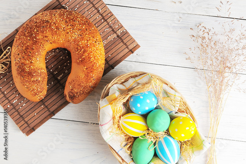 Easter eggs in the nest and bread on rustic white background. Traditional easter cake