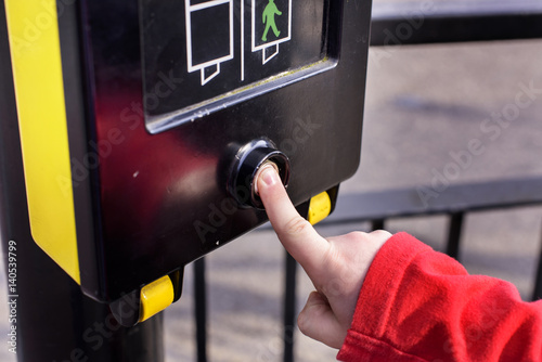 Close up of young boy pressing button to PELICON crossing. He is waiting for the green man to flash before crossing the road