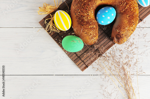 Easter eggs in the nest and bread on rustic white background. Traditional easter cake
