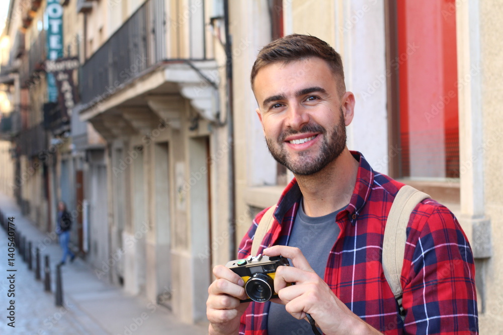 Handsome traveler about to take a pic with a vintage film camera in a European town Handsome traveler about to take a pic with a vintage film camera in a European town