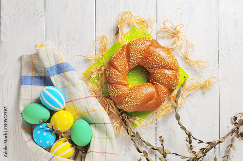 Easter eggs in the nest and bread on rustic white background. Traditional easter cake