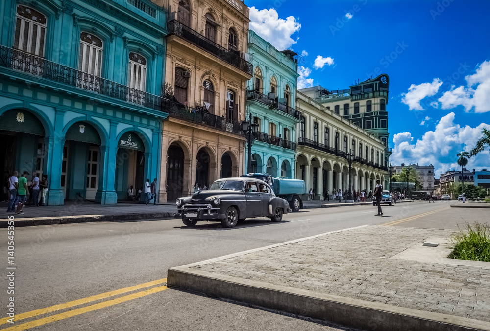 Fototapeta premium HDR - Amerikanischer schwarzer Chevrolet Oldtimer fährt an der historischen Häuserfront der Hauptstrasse vorbei in Havanna Kuba - Serie Kuba Reportage