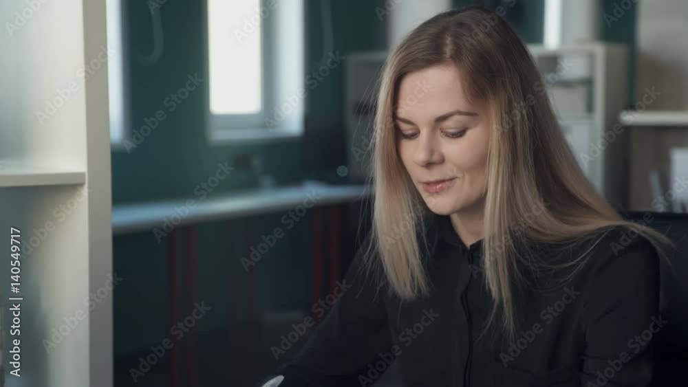 Manager discussing contract to enter with client inside office. blonde with long straight hair, black shirt says, explains conditions of cooperation for interlocutor indoors. Fair-haired woman sitting Manager discussing contract to enter with client inside office. blonde with long straight hair, black shirt says, explains conditions of cooperation for interlocutor indoors. Fair-haired woman sitting