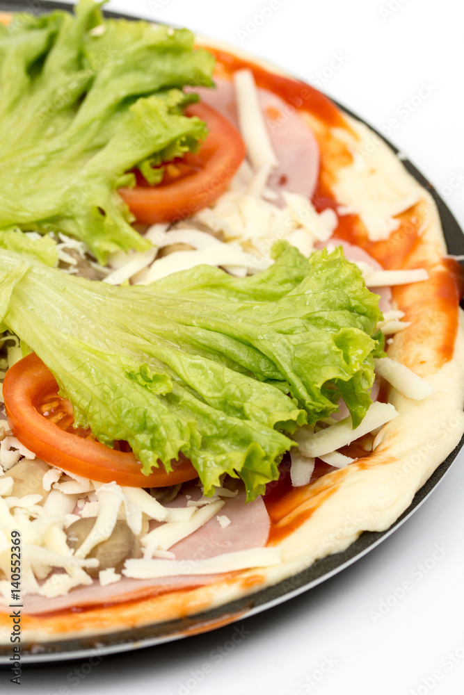 Preparing pizza with lettuce and tomato over white background Preparing pizza with lettuce and tomato over white background