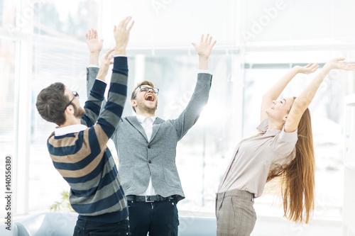  concept of victory - the jubilant business team standing in a circle, hands up in rejoice success.