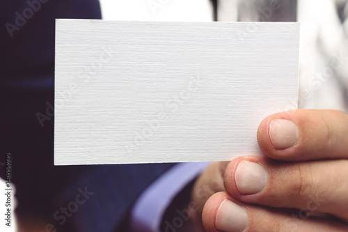 Man hand holding white business card, close-up, selective focus.