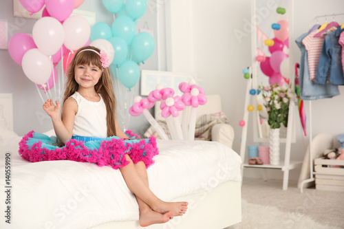 Cute girl sitting on bed in...