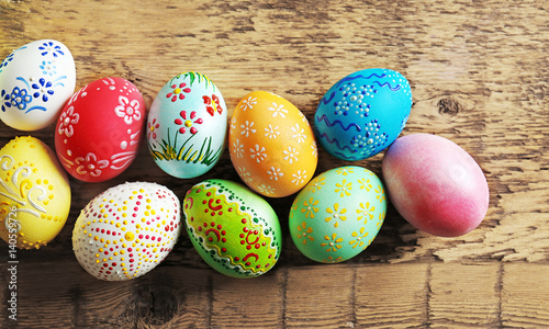 Colourful Easter eggs with floral ornament on wooden background, closeup