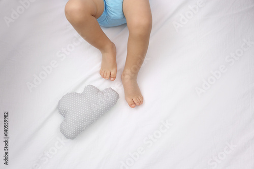 Little baby legs on bed with toy