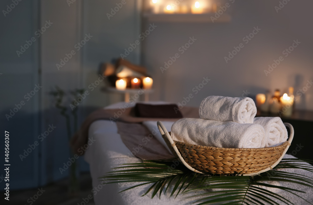 Spa towels in wicker basket on massage table - obrazy, fototapety, plakaty 