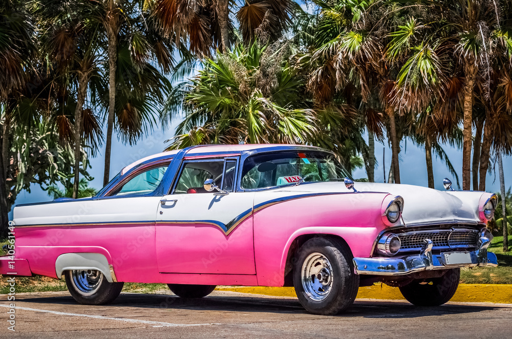 HDR -  Weiß rosa amerikanischer Oldtimer parkt unter Palmen nahe des Strandes in Varadero Kuba - Serie Kuba Reportage