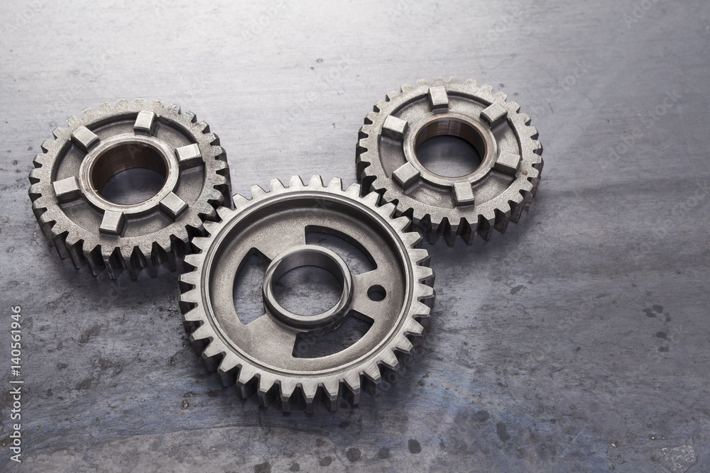 A group of solid metal gears are linked together on a grungy steel background. This set of industrial cog wheels can be used to represent the concept of team work. A group of solid metal gears are linked together on a grungy steel background. This set of industrial cog wheels can be used to represent the concept of team work.