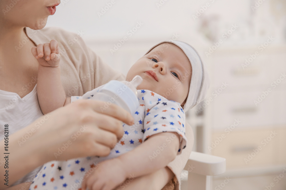 Young woman feeding cute little baby at home, closeup Young woman feeding cute little baby at home, closeup