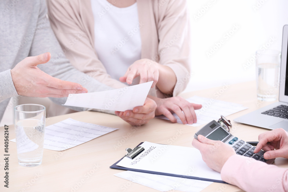 Fototapeta premium Young couple signing contract at insurance agency office